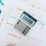 Kalkulator dan laporan keuangan di atas meja sebagai ilustrasi perhitungan BEP bisnis