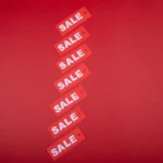 Label harga berwarna merah yang tertata di atas latar merah, menggambarkan strategi penetapan markup harga dalam bisnis retail